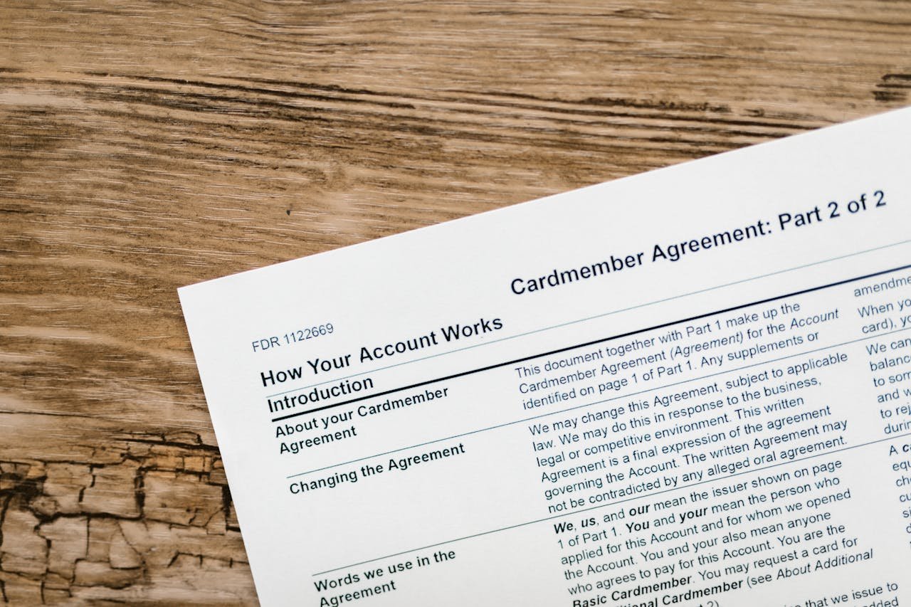 Close-up of a credit card agreement document on a textured wooden desk.